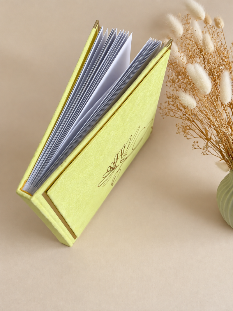 Kollane sametine fotoalbum Kollane sametine fotoalbum valgete lehtede, kuldsete nurgakaitsmete ja minimalistliku lillemustriga kaanel.